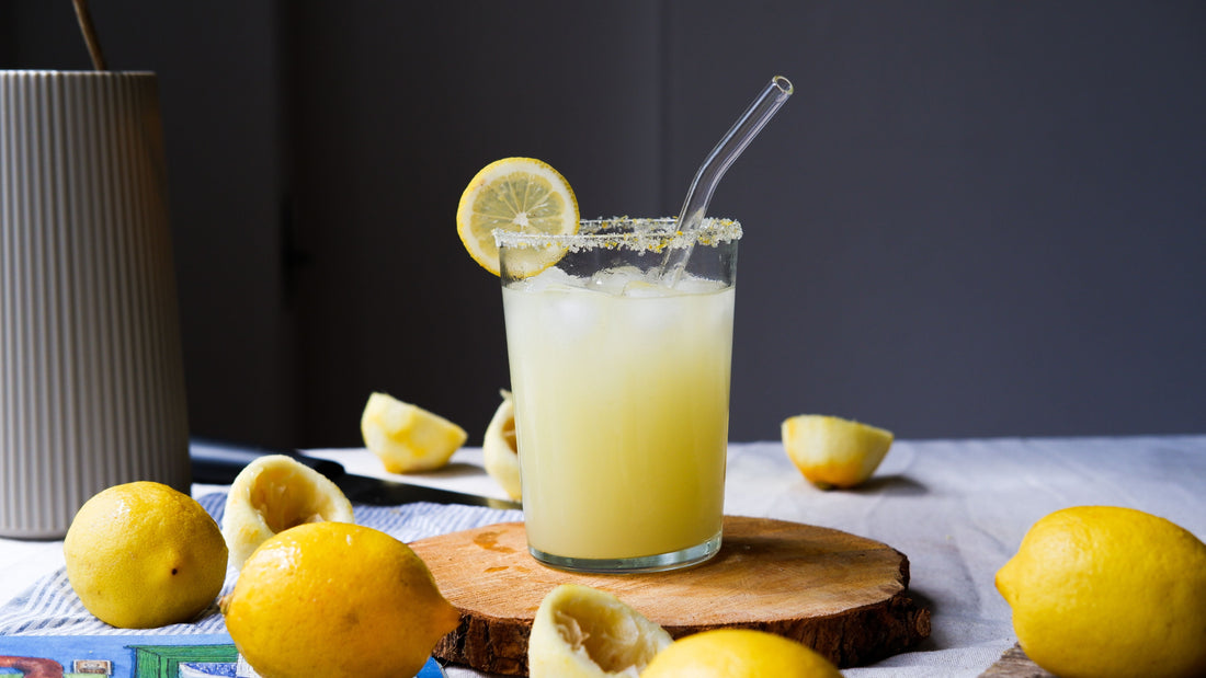 A halved lemon and glass of fresh citrus juice on a white surface — lemon tek microdosing nausea remedy